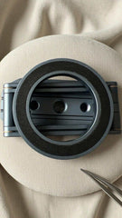 Close-up of a black metal ring on a beige fabric background